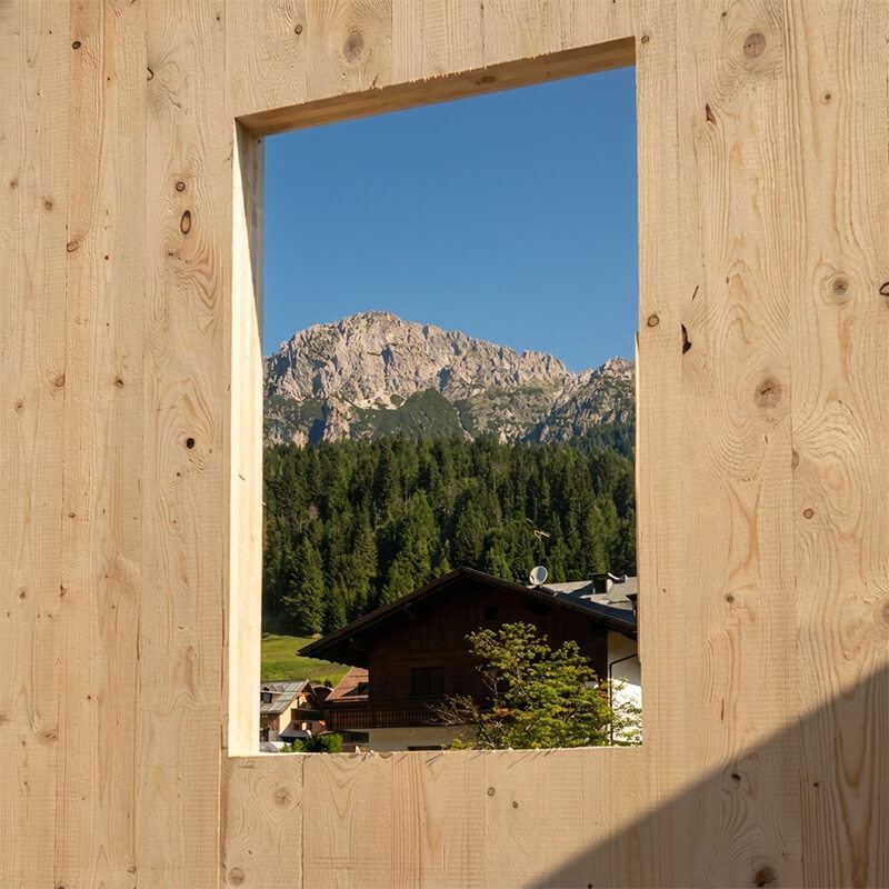 Apertura in una parete di legno XLAM che inquadra le Dolomiti